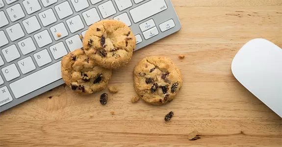 um teclado de compuador sobre uma madeira e cookies de chocolate